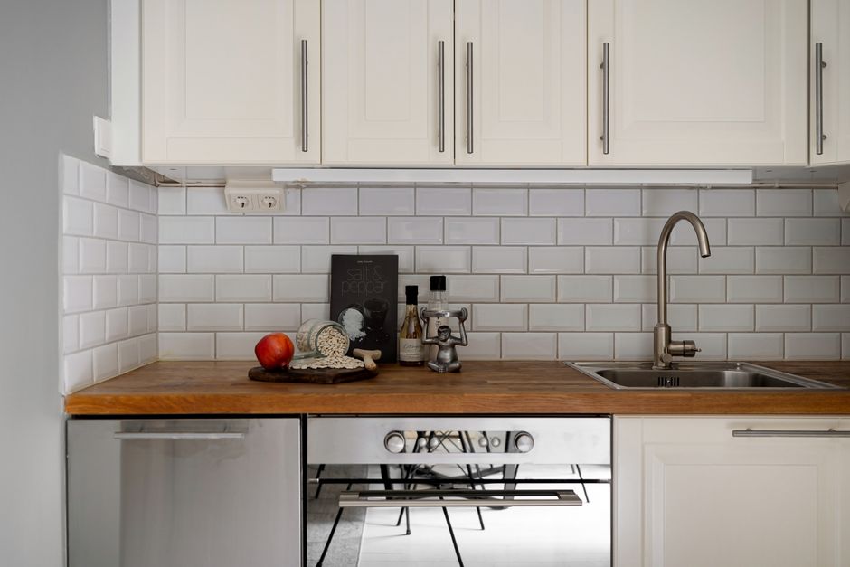 Stylish modern kitchen interior with white cabinets and wooden countertop, featuring kitchen essentials.