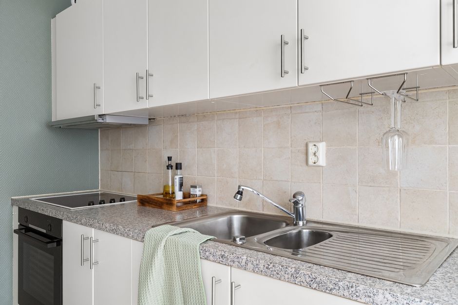 Sleek modern kitchen with granite countertops, stainless steel sink, and white cabinets.